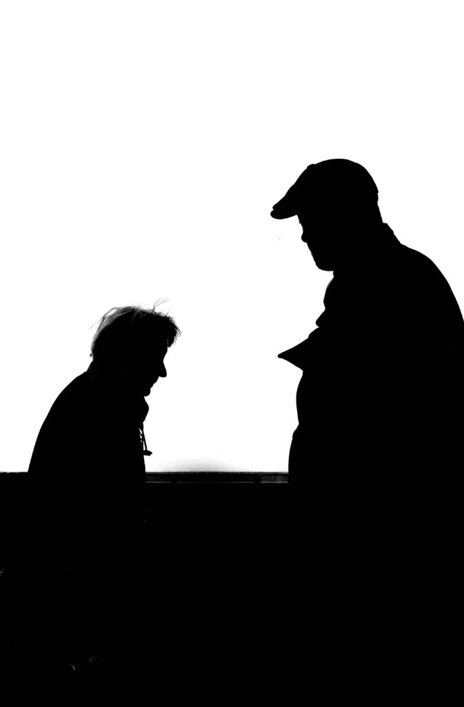 High contrast silhouette photo capturing two adults conversing against a white background.